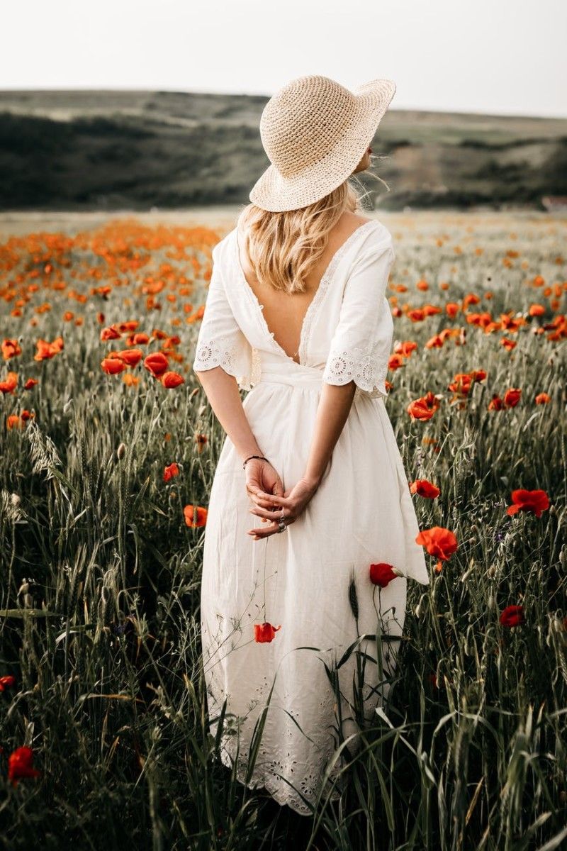 unrecognizable woman in white dress in countryside field